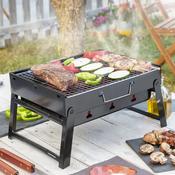 Barbecue Pieghevole Portatile a Carbone BearBQ con carni e verdure sulla griglia.