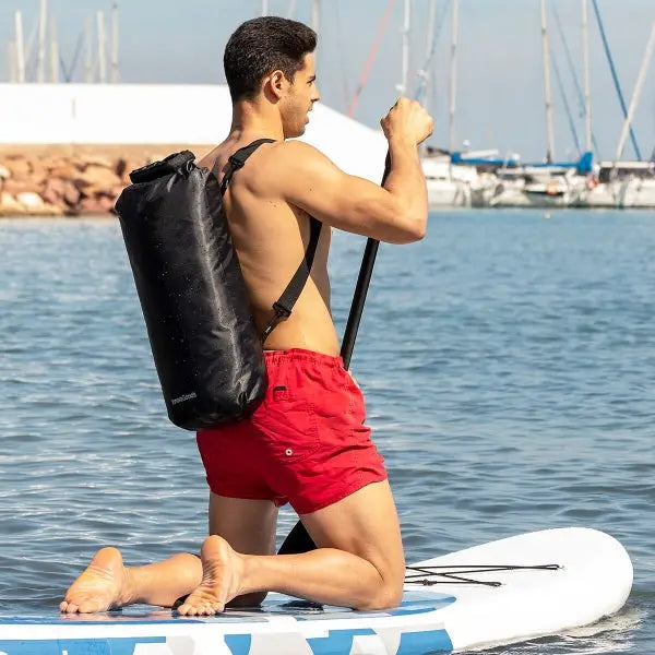 Shirtless man on paddleboard with Dryhux sports dry bag in black.